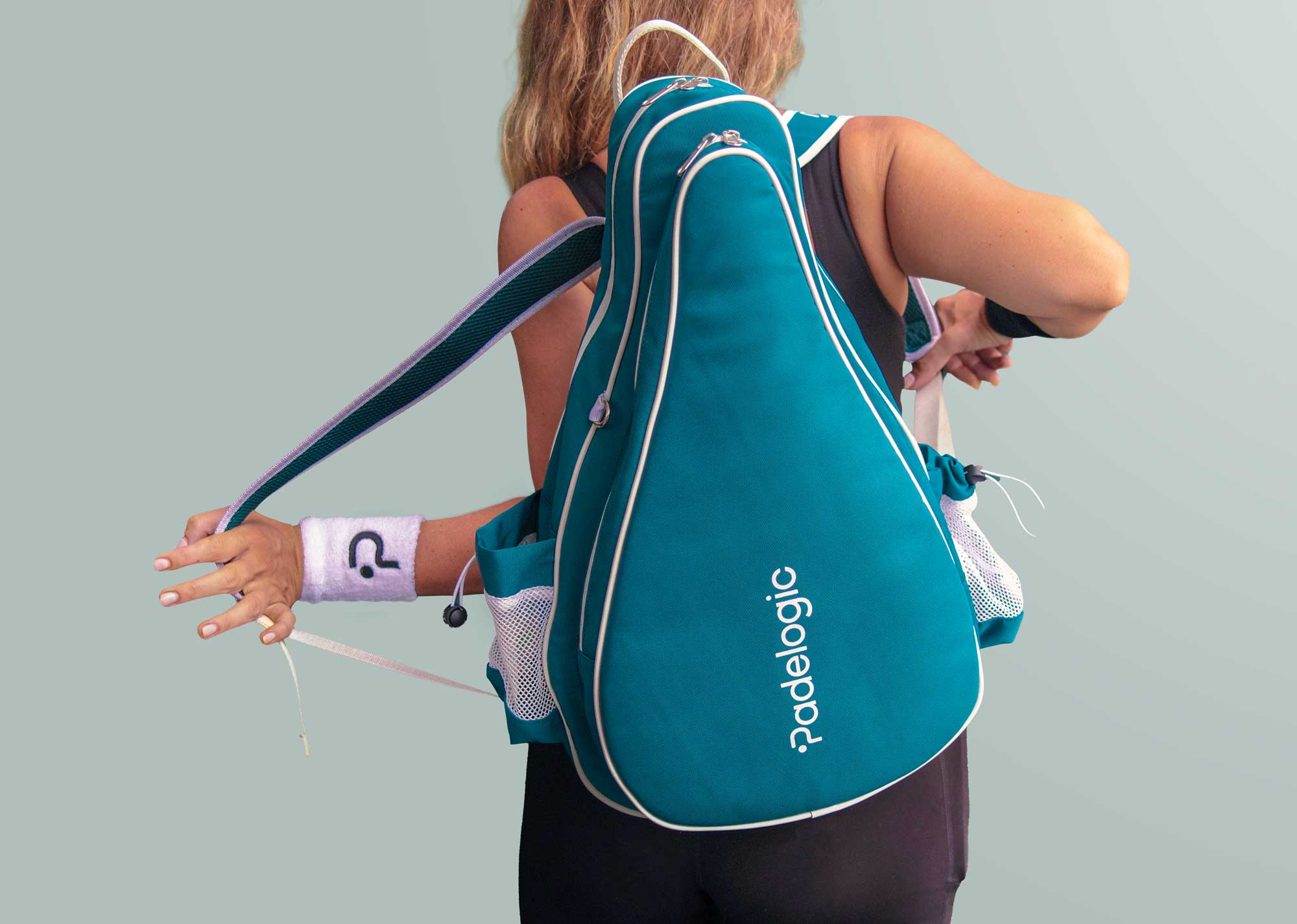 Girl wearing a teal padel bag with 'padelogic' branding on a gray background