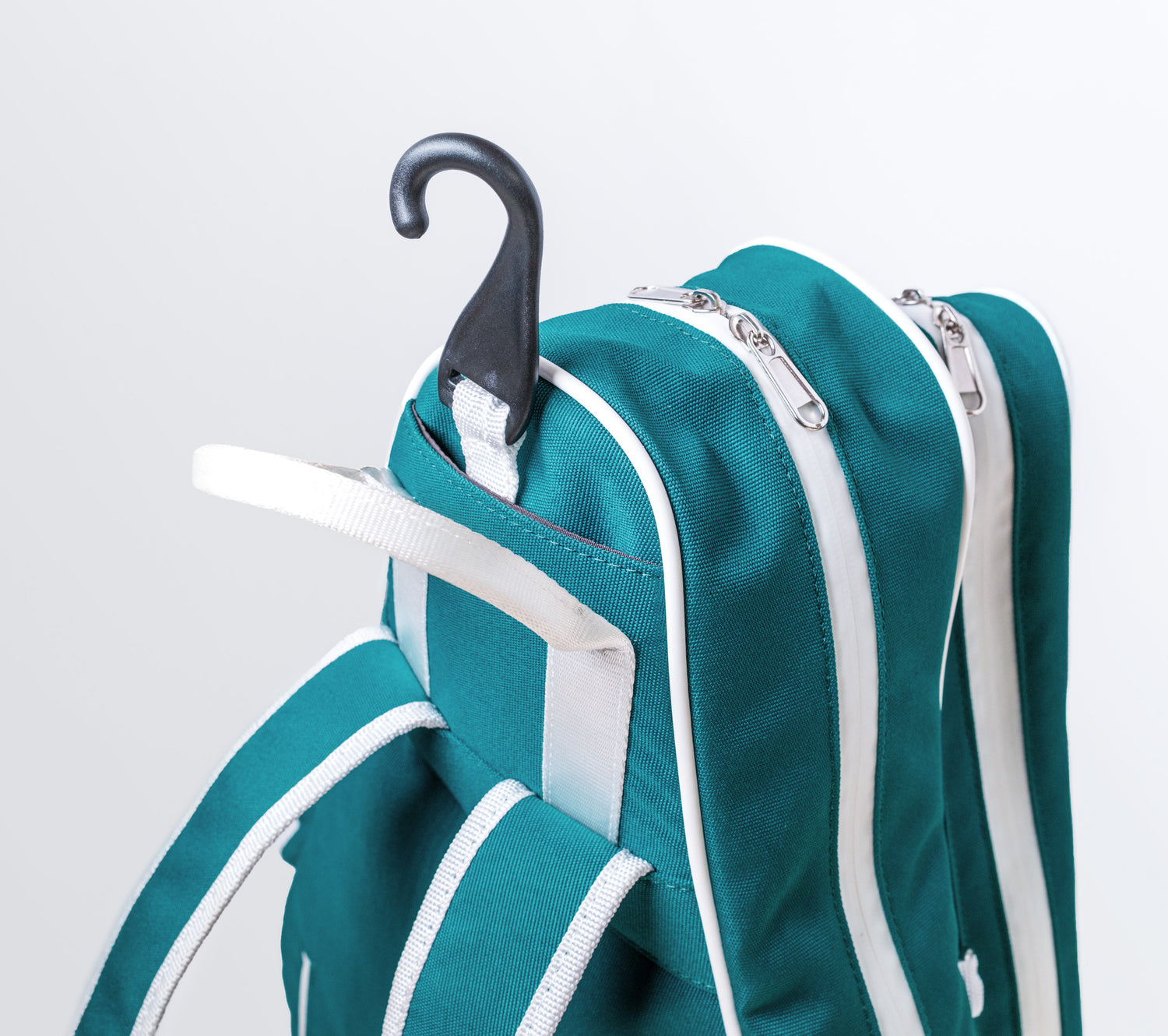 Teal padel bag with white zippers and straps on a light gray background with hook
